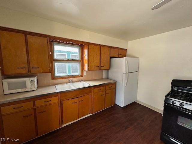 kitchen featuring sink, backsplash, dark hardwood / wood-style floors, and white appliances