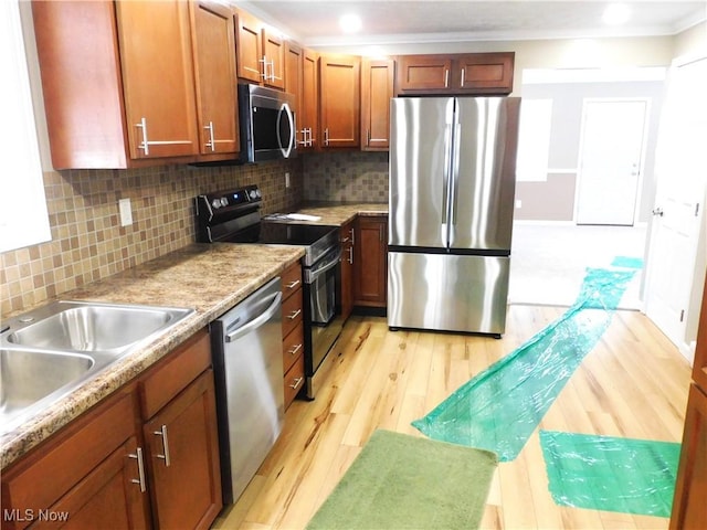 kitchen featuring appliances with stainless steel finishes, sink, backsplash, ornamental molding, and light wood-type flooring