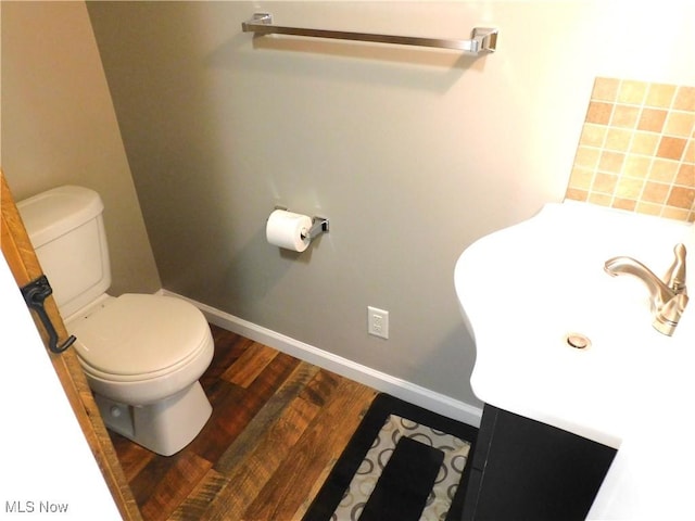 bathroom with toilet, hardwood / wood-style floors, and vanity