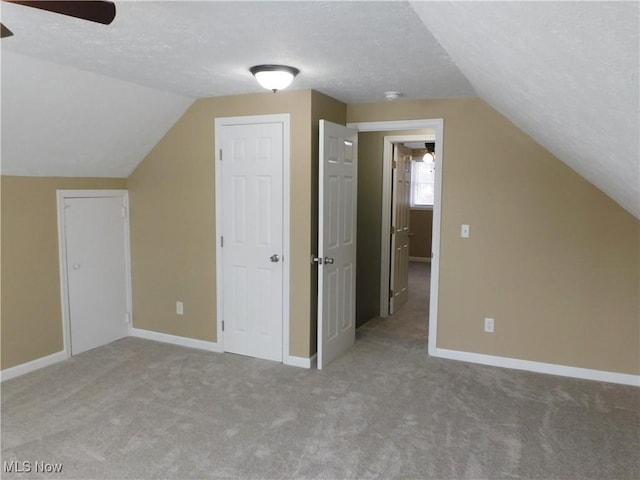 bonus room featuring ceiling fan, light colored carpet, a textured ceiling, and lofted ceiling