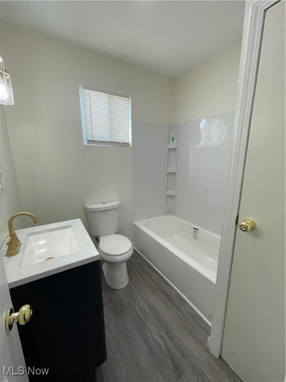 full bathroom with toilet, vanity,  shower combination, and hardwood / wood-style floors