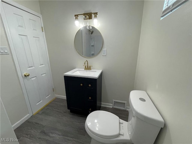 bathroom featuring toilet, vanity, and hardwood / wood-style floors