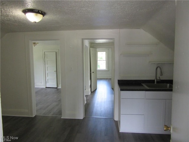 kitchen featuring dark wood-type flooring, sink, white cabinetry, and a textured ceiling