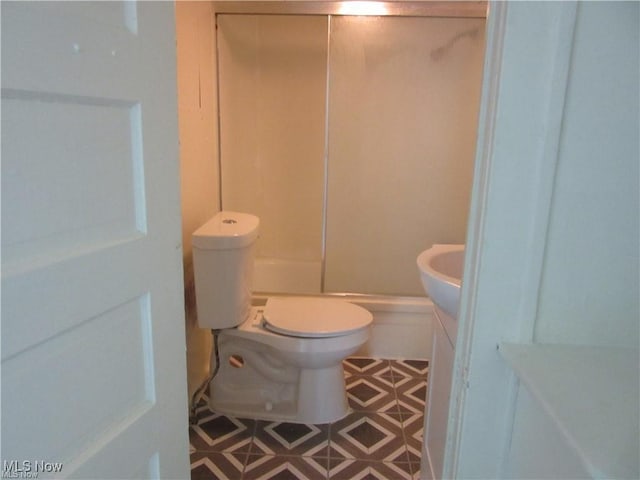 bathroom featuring a shower with shower door, toilet, and vanity