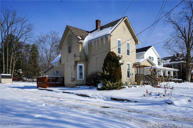 snow covered rear of property featuring a wooden deck