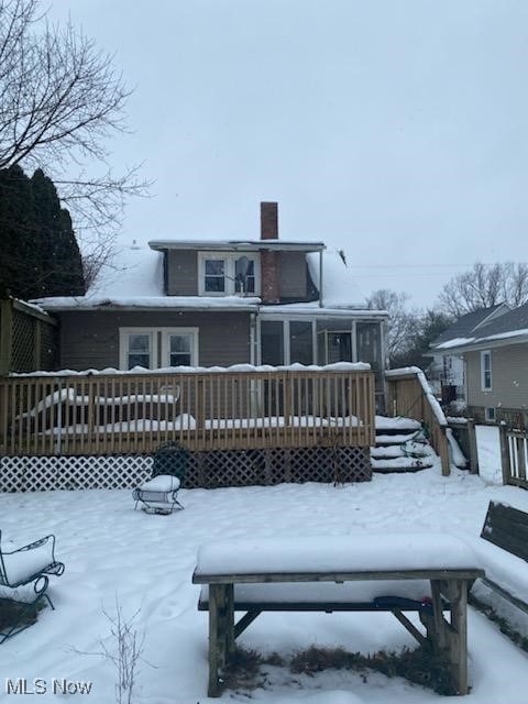 snow covered rear of property with a deck