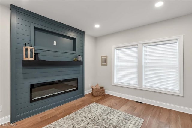 living room featuring hardwood / wood-style flooring and a large fireplace