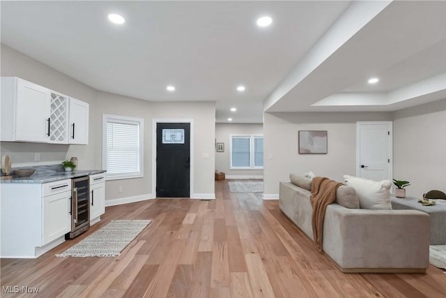 living room featuring bar area, beverage cooler, and light hardwood / wood-style flooring