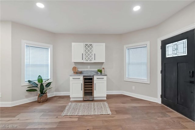 bar with white cabinets, light wood-type flooring, and beverage cooler