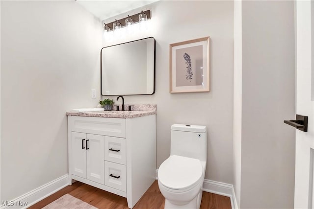 bathroom with hardwood / wood-style flooring, toilet, and vanity