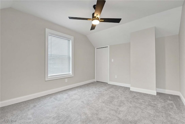 unfurnished room with ceiling fan, light colored carpet, and vaulted ceiling