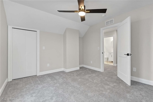 unfurnished bedroom with ceiling fan, light colored carpet, a closet, and lofted ceiling