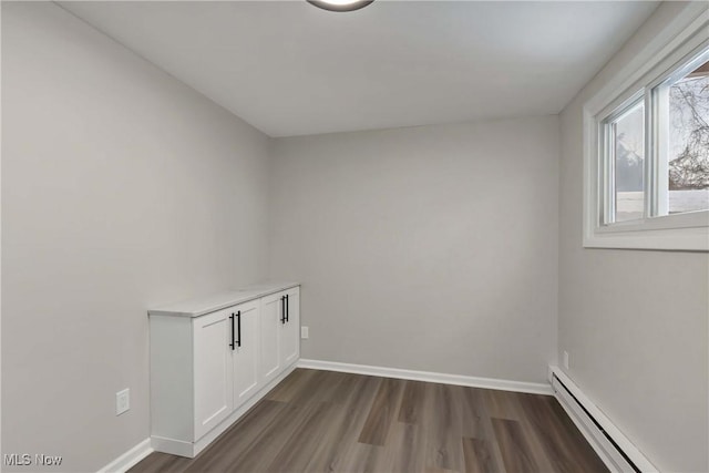 laundry room with a baseboard heating unit and dark wood-type flooring