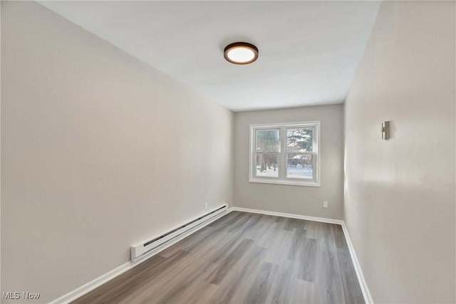 unfurnished room featuring wood-type flooring and a baseboard heating unit