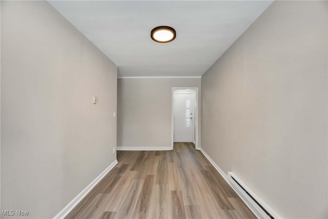 corridor with a baseboard heating unit and light hardwood / wood-style floors