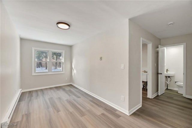 spare room featuring sink, wood-type flooring, and a baseboard radiator