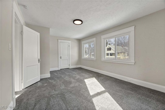 unfurnished bedroom with dark carpet and a textured ceiling