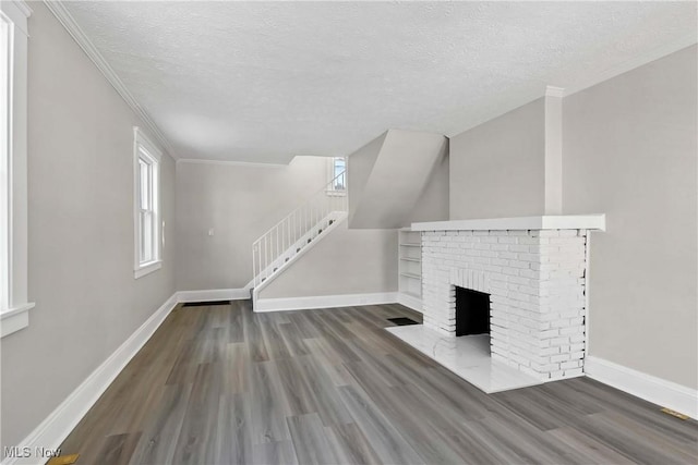 unfurnished living room with a textured ceiling, dark hardwood / wood-style flooring, ornamental molding, and a fireplace