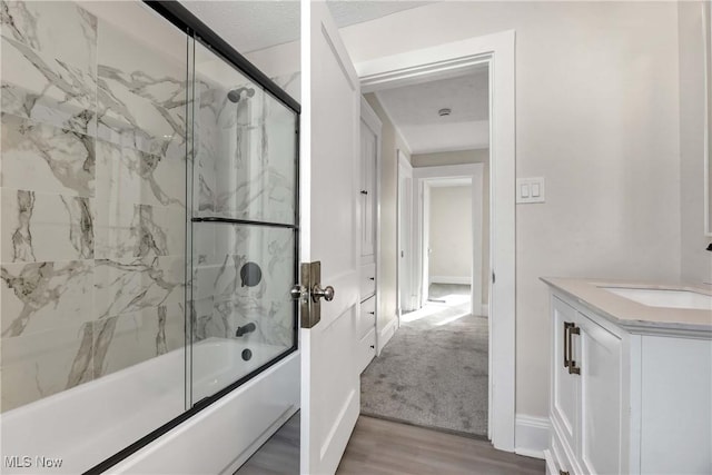 bathroom with wood-type flooring, shower / bath combination with glass door, vanity, and a textured ceiling