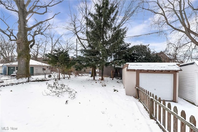 yard layered in snow featuring a garage and an outdoor structure