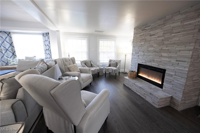 living room with dark wood-type flooring and a stone fireplace