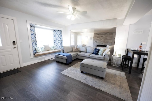 living room featuring dark wood-type flooring, ceiling fan, a textured ceiling, and a fireplace