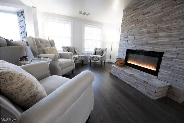 living room with dark wood-type flooring, a healthy amount of sunlight, and a fireplace