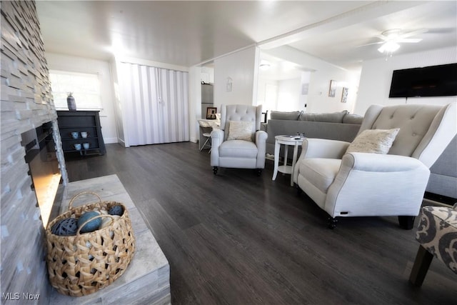 living room featuring ceiling fan, dark hardwood / wood-style flooring, and a fireplace