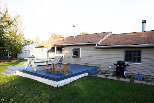 rear view of property featuring a wooden deck and a lawn