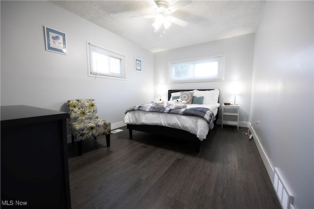 bedroom with ceiling fan, multiple windows, dark hardwood / wood-style flooring, and a textured ceiling