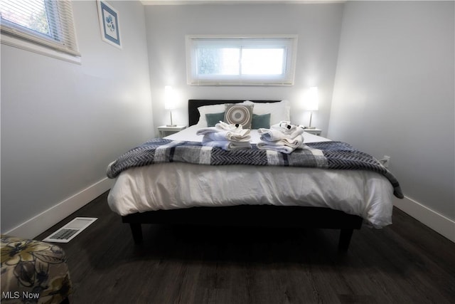 bedroom with dark hardwood / wood-style flooring and multiple windows