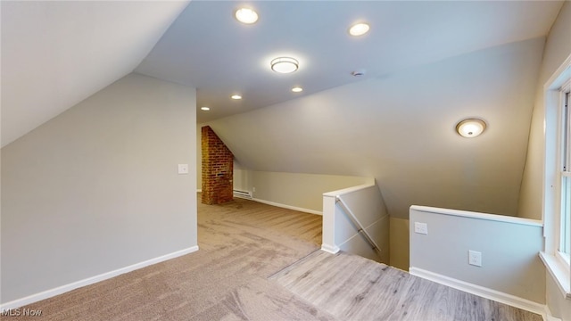 bonus room featuring a baseboard heating unit, light carpet, and vaulted ceiling