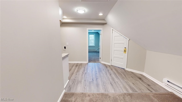 additional living space with light hardwood / wood-style floors, baseboard heating, and vaulted ceiling