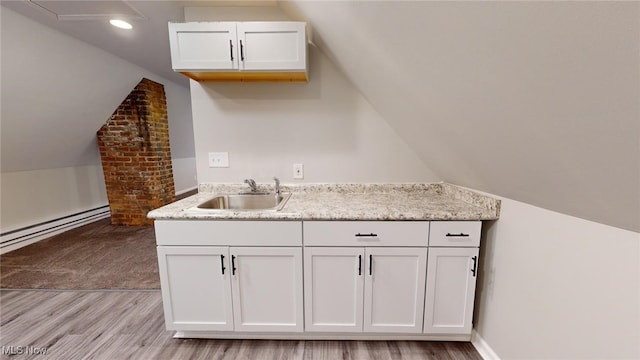 kitchen featuring lofted ceiling, sink, and white cabinetry