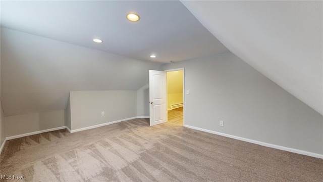 bonus room featuring a baseboard heating unit, lofted ceiling, and light carpet