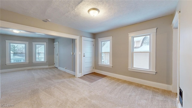 unfurnished room with light colored carpet and a textured ceiling