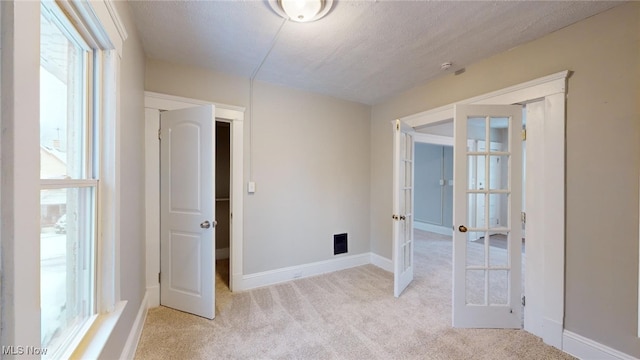 carpeted spare room with a textured ceiling and french doors