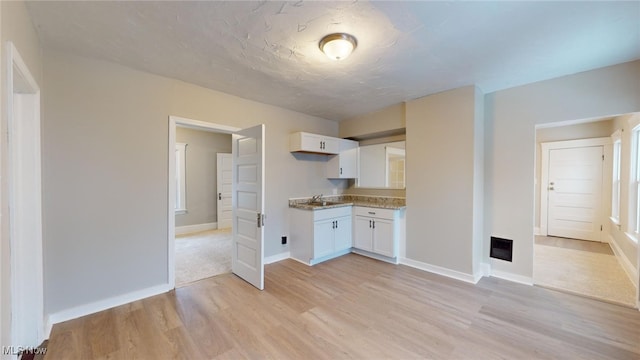 kitchen with light hardwood / wood-style flooring, white cabinets, and sink