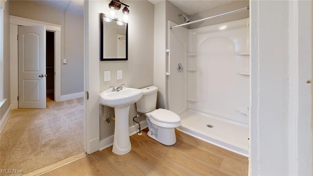 bathroom with a shower, sink, hardwood / wood-style flooring, and toilet