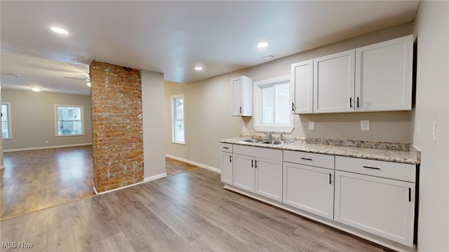 kitchen featuring light wood-type flooring, sink, white cabinetry, and decorative columns