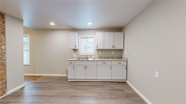 kitchen featuring sink, white cabinetry, light hardwood / wood-style flooring, and a healthy amount of sunlight