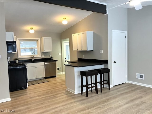 kitchen featuring stainless steel dishwasher, a kitchen bar, sink, black gas stove, and white cabinetry