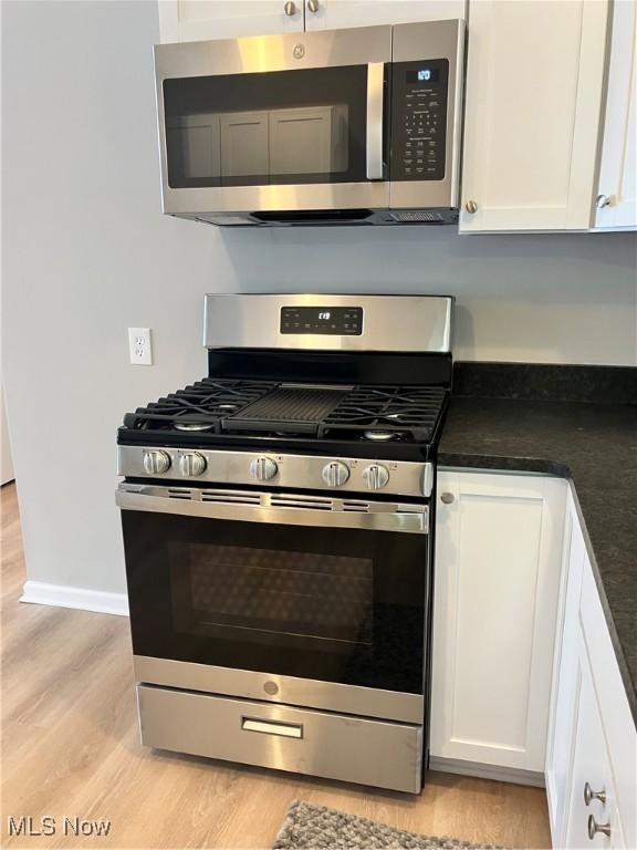 kitchen with stainless steel appliances, light hardwood / wood-style flooring, and white cabinets