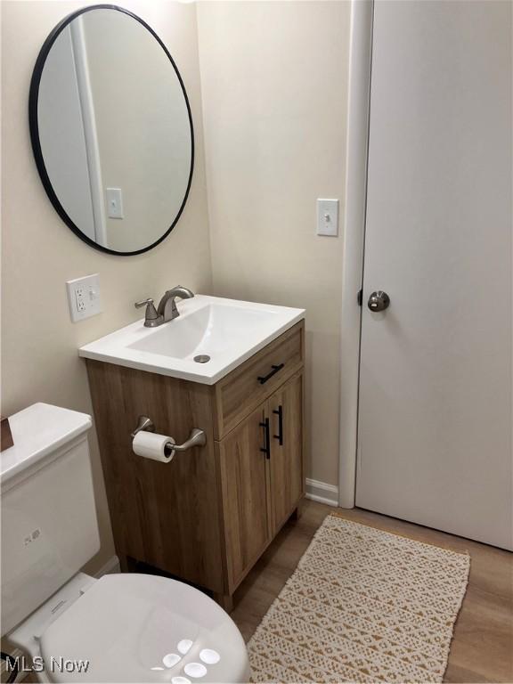 bathroom featuring wood-type flooring, toilet, and vanity