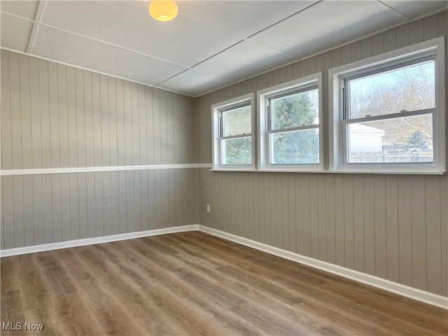 unfurnished room with plenty of natural light and wooden walls