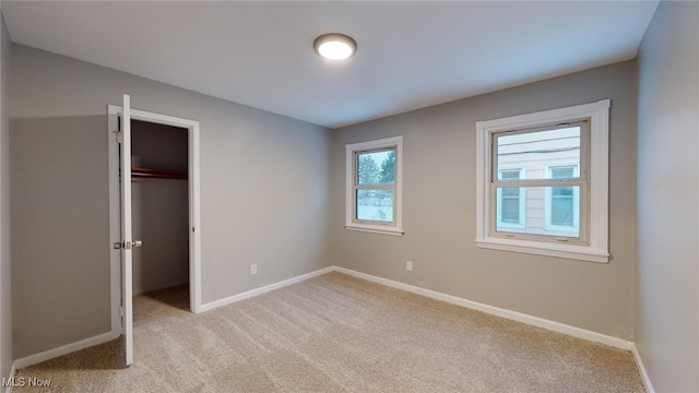 unfurnished bedroom with light carpet, a closet, and a spacious closet