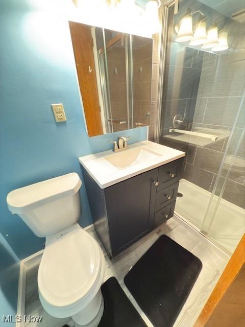 bathroom with toilet, a stall shower, and vanity