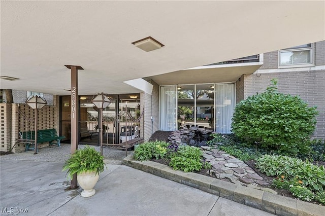 doorway to property with brick siding, a patio area, and visible vents