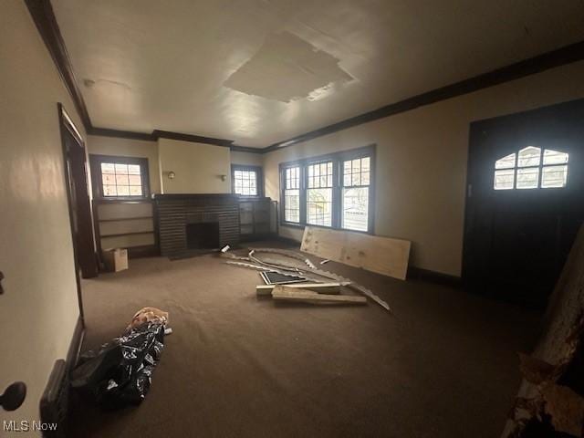 interior space with a fireplace, ornamental molding, and carpet flooring