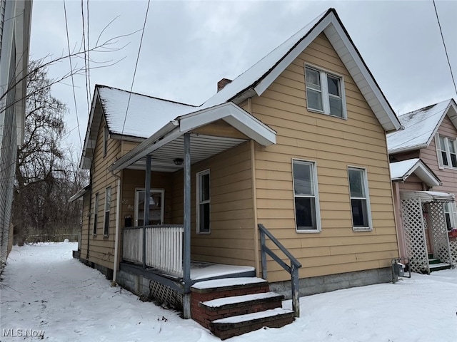 snow covered house featuring a porch